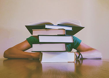 Schüler am Schreibtisch, Arme und Stapel Bücher zu sehen
